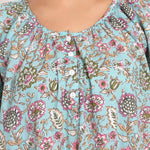 Detail view of neckline with buttons and gathered fabric in aqua floral print.