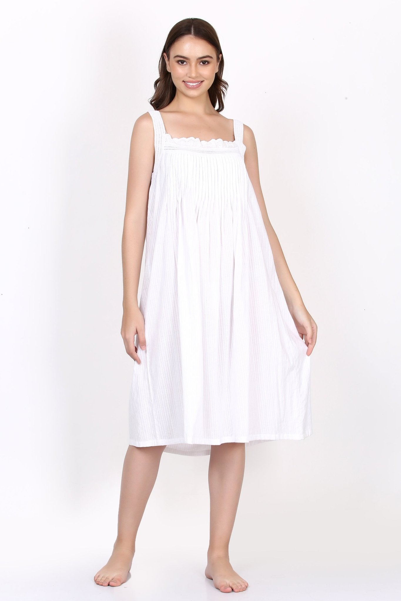 Model in white strappy cotton nightie with pintuck detail and broderie lace neckline, front view.