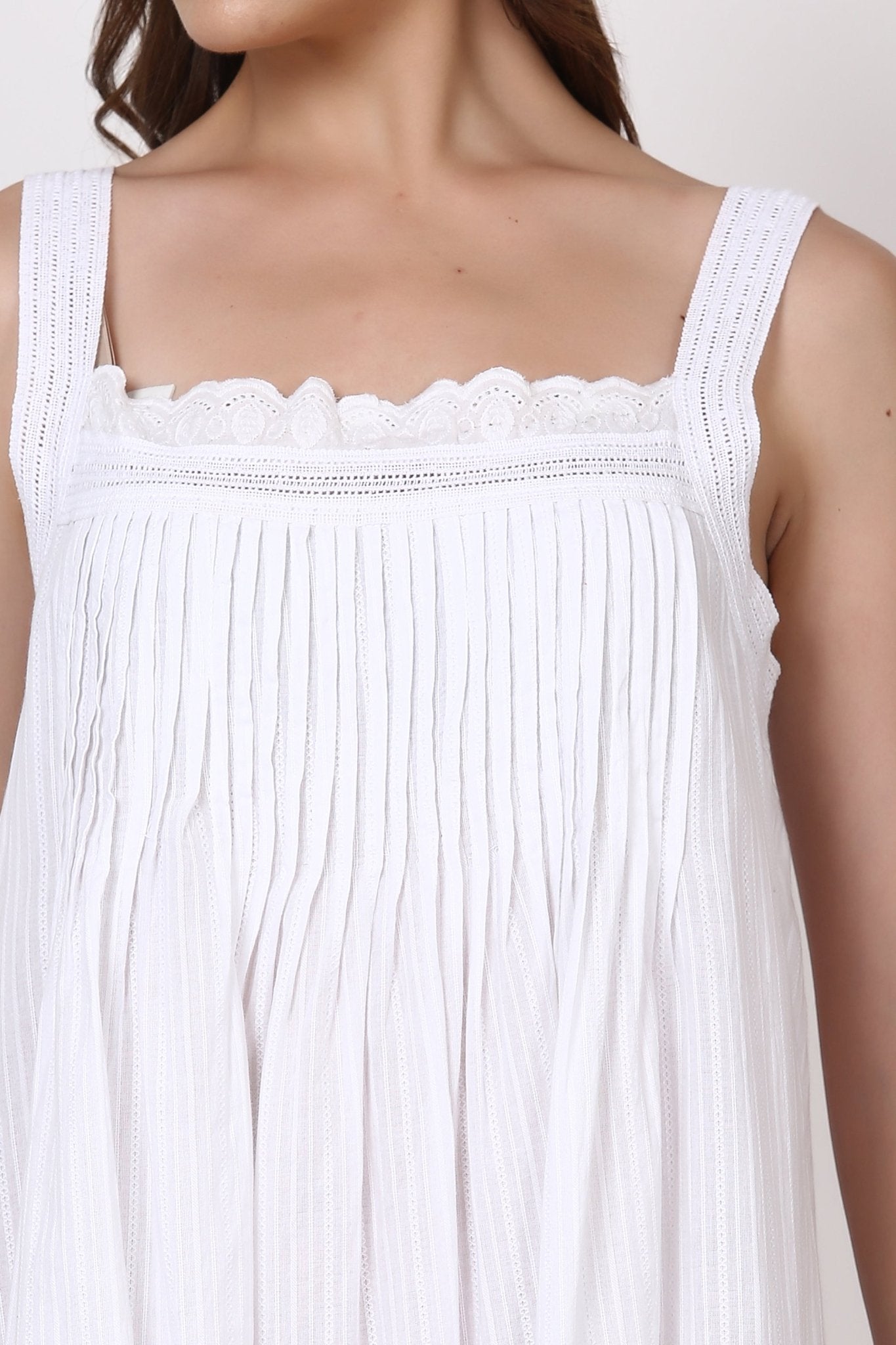 Close-up of pintuck bodice and square neckline with broderie lace detail on white nightie.