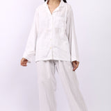 Woman wearing Lotus Jacqui revere long pyjama set in white self-stripe cotton, shirt and pants.