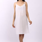 Woman wearing Lotus bias cut white cotton slip with slim straps, ideal as petticoat or summer nightie.