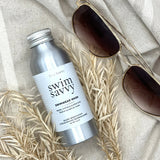 Swim Savvy Laundry Liquid and wash bag on a natural surface with summer essentials.