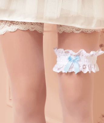 Model wearing white lace garter with light blue bow, from The Foundation, a perfect “something blue” under a wedding dress for a classic bridal touch.