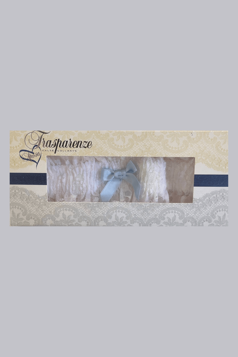 White lace garter with light blue bow by Trasparenze, boxed, available at The Foundation—classic bridal accessory for the “something blue” tradition.