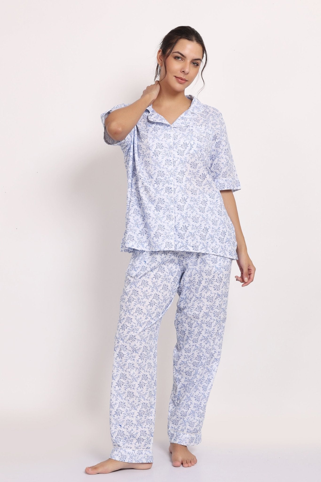 Woman wearing a light blue floral short sleeve pyjama set with loose-fitting top and matching long pants, styled for relaxed comfort and breathable sleepwear.
