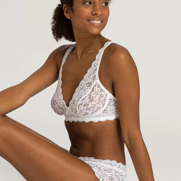 Model wearing Hanro Moments Soft Cup Bra and Briefs in White lace, seated against a neutral background