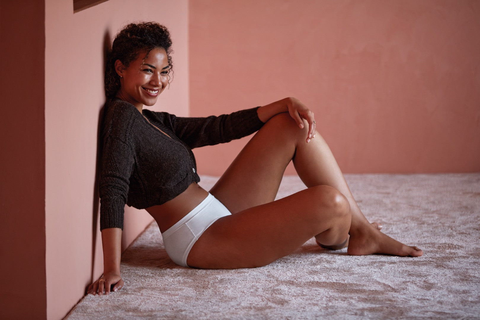 Woman wearing seamless white cotton underwear sitting comfortably against a soft neutral background
