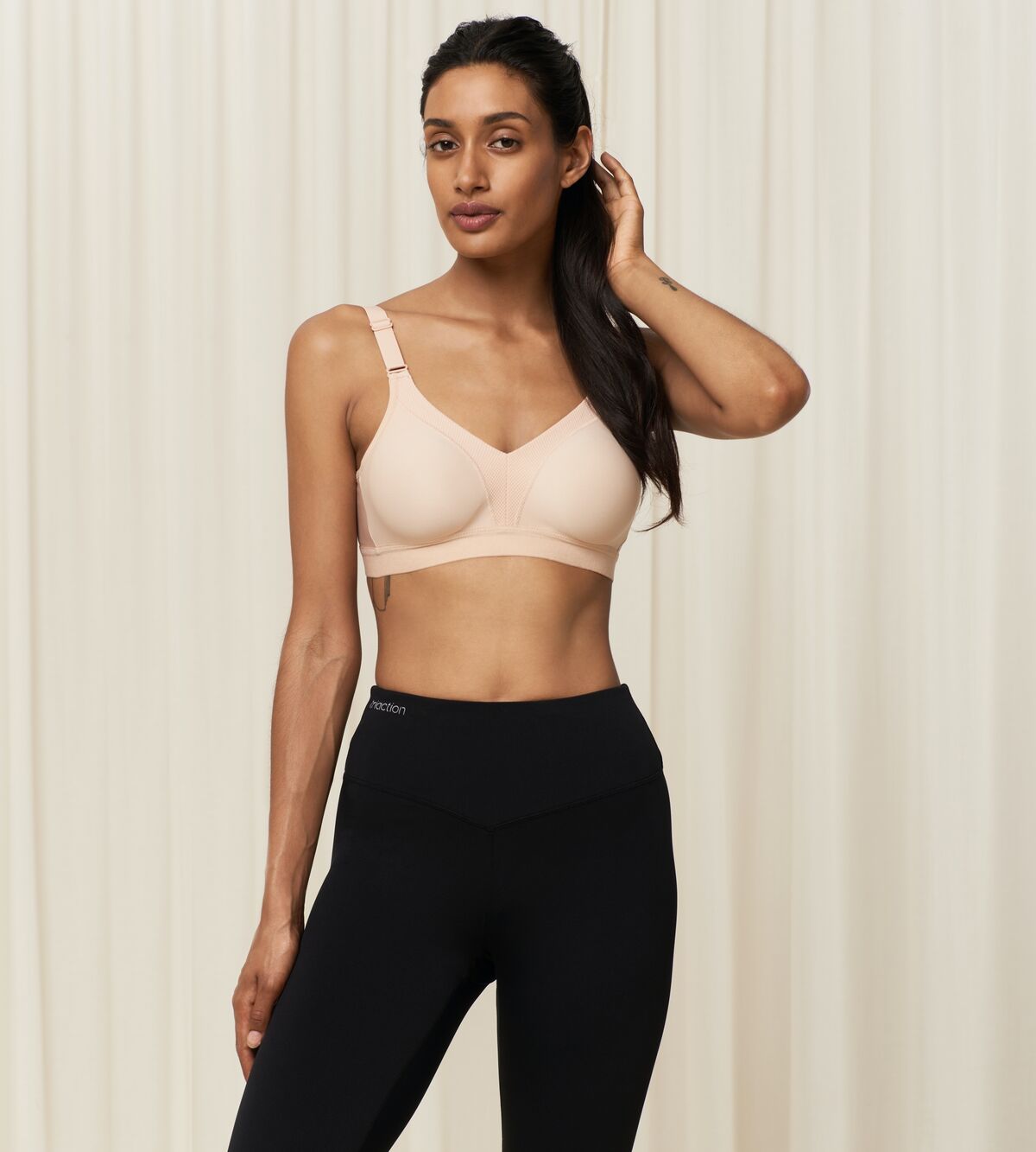 Woman wearing the Triaction Wellness Bra in Neutral Beige, showcasing soft wireless support and adjustable straps, ideal for light-impact workouts.