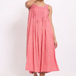 Model wearing coral cotton strappy nightie with subtle self-stripe, front view with raised arm.