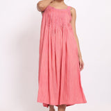 Model wearing coral cotton strappy nightie with subtle self-stripe, front view with raised arm.