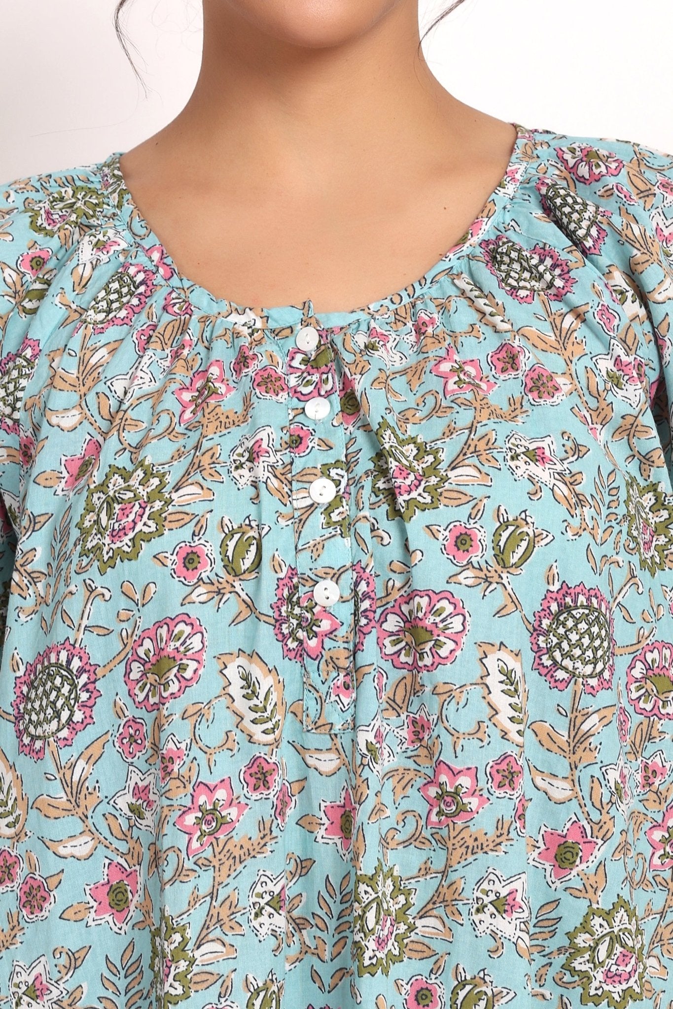 Detail view of neckline with buttons and gathered fabric in aqua floral print.