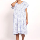 Model wearing cap sleeve cotton nightie in white with navy floral print.