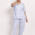 Model wearing floral cotton PJ set with short sleeves and full-length pants, smiling with hand on hip.