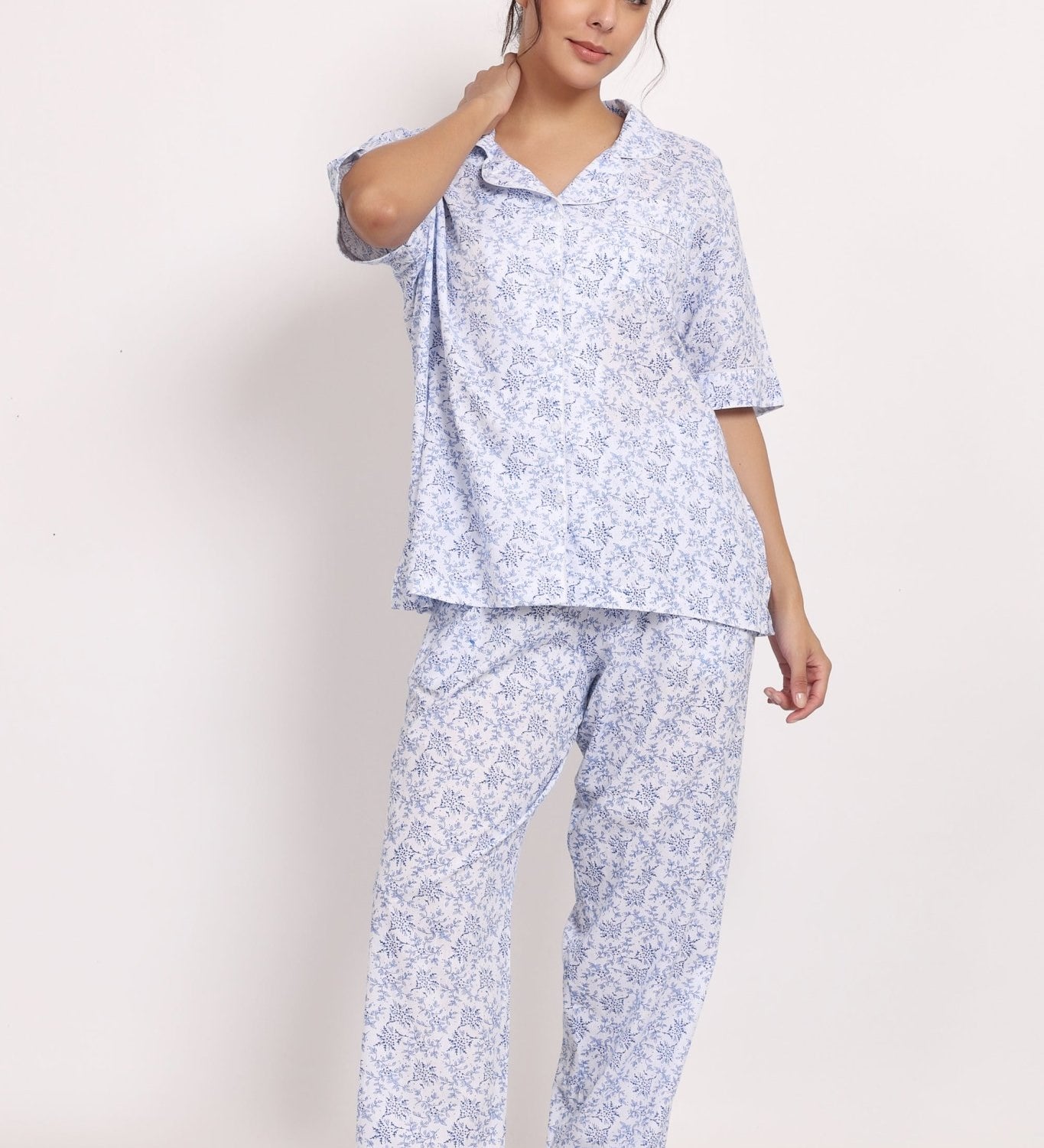 Model wearing floral cotton PJ set with short sleeves and full-length pants, smiling with hand on hip.