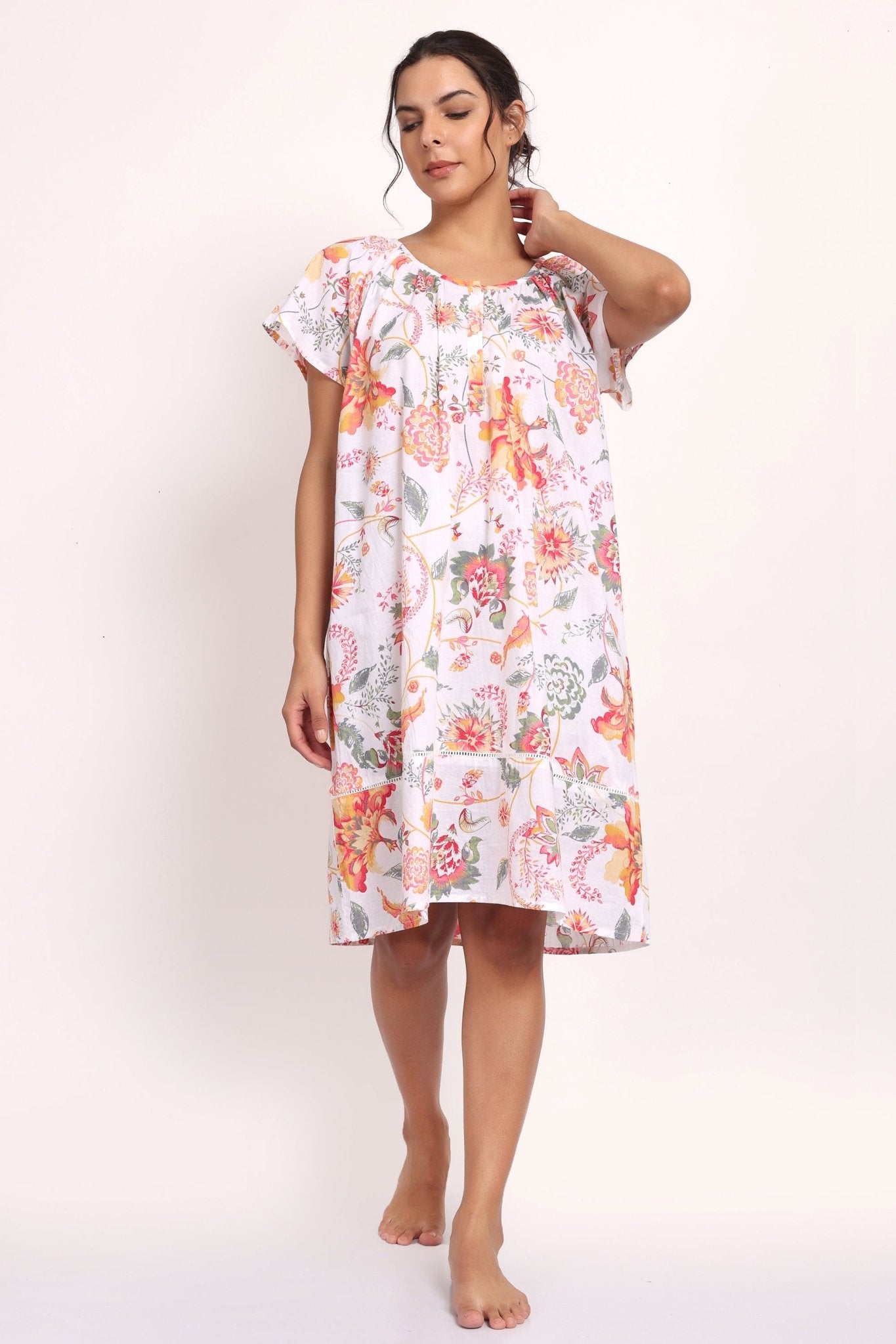 Model in peach botanical print cotton nightie with cap sleeves and knee-length cut.
