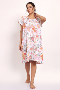 Model in peach botanical print cotton nightie with cap sleeves and knee-length cut.