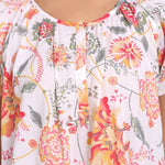 Detailed view of buttoned neckline with softly gathered pleats and coral floral print.