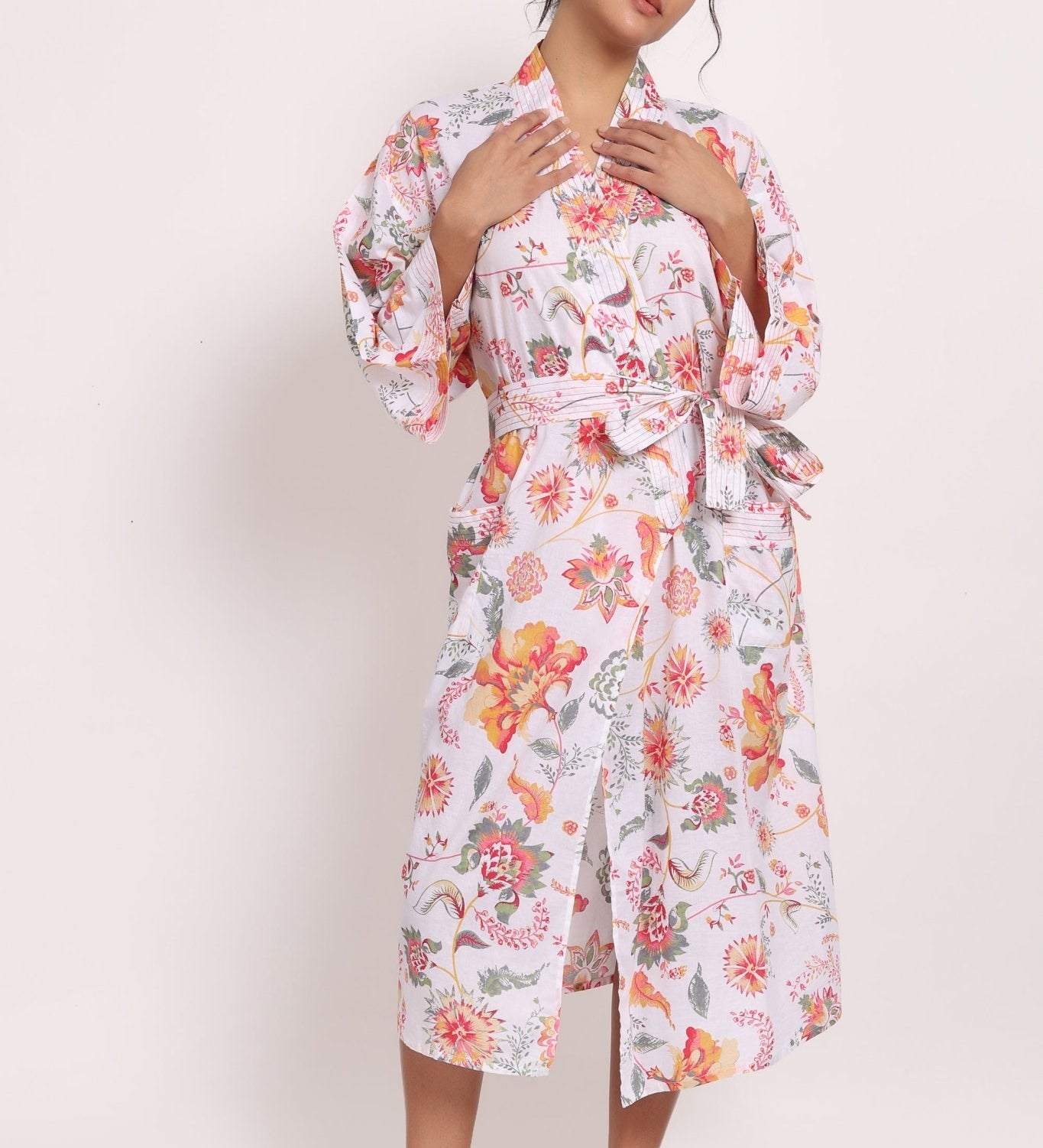 Model wearing Passionflower Kimono in coral print, featuring wide lapels, tie belt and relaxed cotton fit.