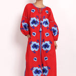 Model in bright red cotton sundress with bold blue floral embroidery, front view.