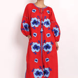Model in bright red cotton sundress with bold blue floral embroidery, front view.