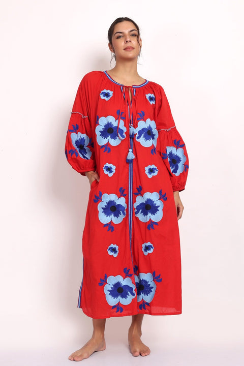 Model in bright red cotton sundress with bold blue floral embroidery, front view.