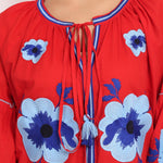 Close-up of v-neckline and tassel tie on red Romani cotton sundress with floral embroidery.