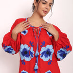 Model smiling in red embroidered sundress showing soft neckline and relaxed drape.