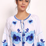 Model smiling in Romani embroidered sundress, close-up on bodice and sleeves.