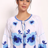 Model smiling in Romani embroidered sundress, close-up on bodice and sleeves.