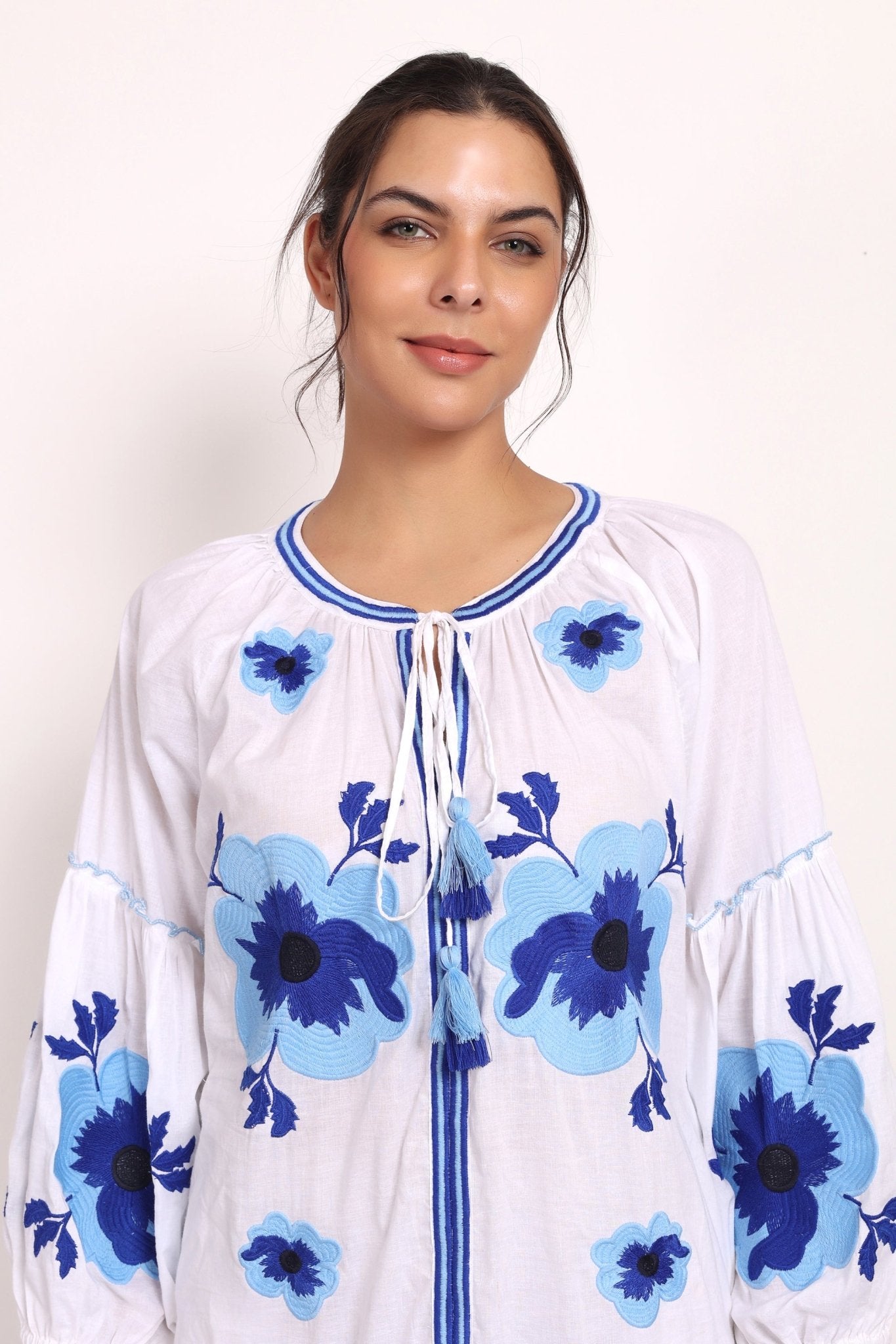 Model smiling in Romani embroidered sundress, close-up on bodice and sleeves.