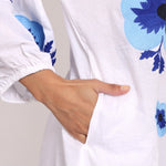 Detailed shot of oversized navy floral embroidery on cotton sleeve.
