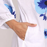 Detailed shot of oversized navy floral embroidery on cotton sleeve.
