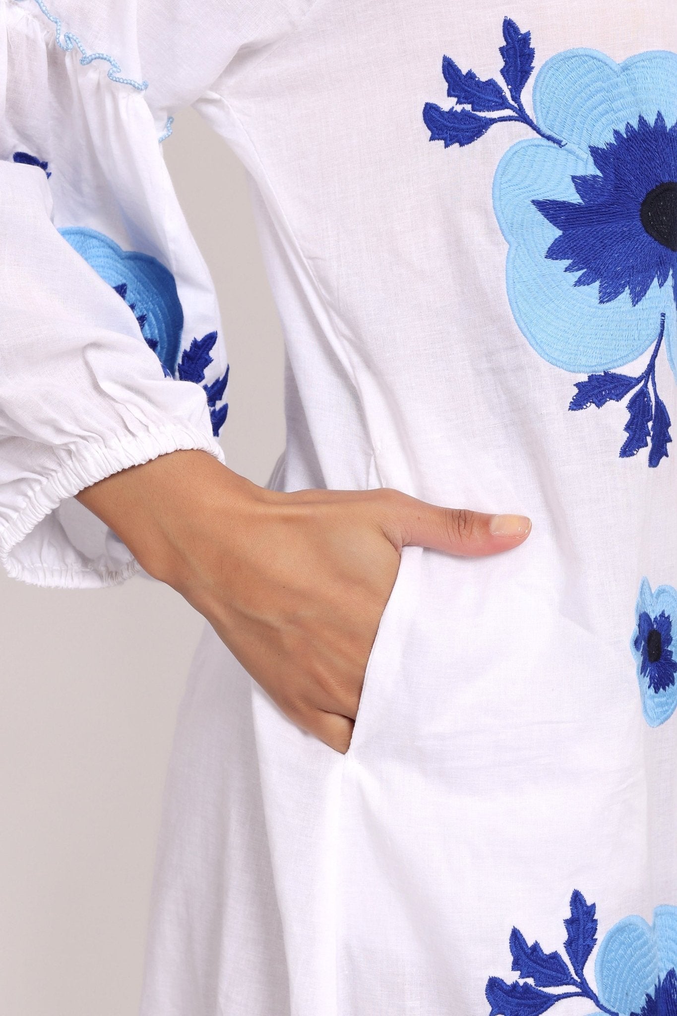 Detailed shot of oversized navy floral embroidery on cotton sleeve.