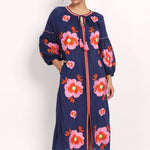 Model wearing navy cotton sundress with pink floral embroidery, front view with raised arm.