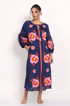 Model wearing navy cotton sundress with pink floral embroidery, front view with raised arm.