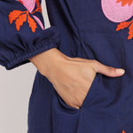 Macro view of oversized pink floral embroidery on navy cotton fabric.