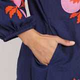 Macro view of oversized pink floral embroidery on navy cotton fabric.