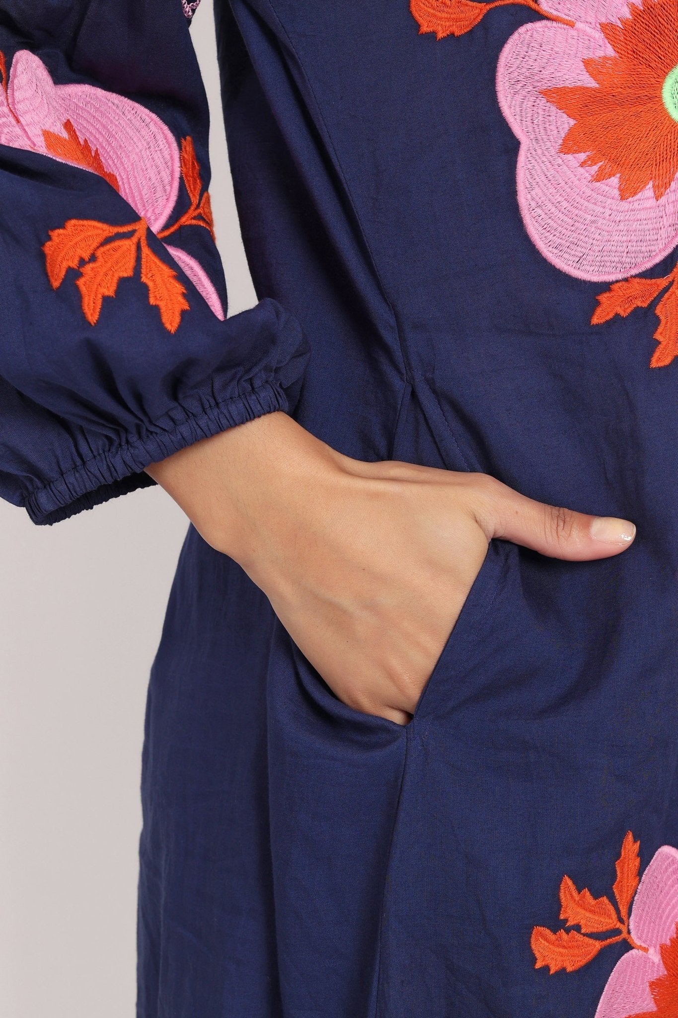Macro view of oversized pink floral embroidery on navy cotton fabric.
