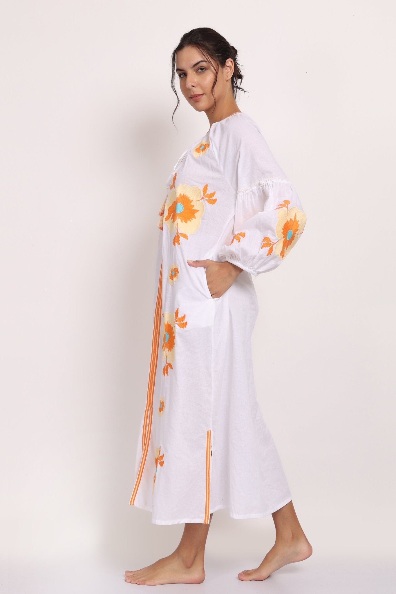 Side view of cotton sundress showing floral embroidery and split hemline.