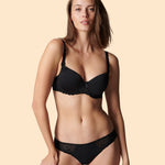 Woman wearing a black bra and panties set on a beige background