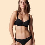 Woman wearing a black bra and panties set on a beige background