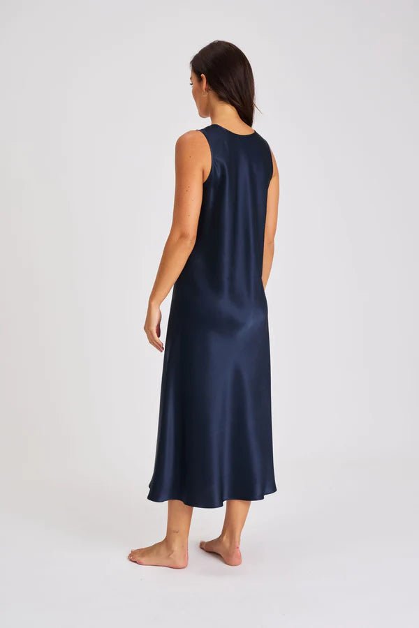 Back view of Model walking in navy long silk chemise showcasing bias-cut drape and elegant movement.