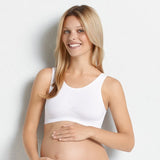 Smiling pregnant model wearing Anita Seamless Maternity Sleep Bra White, showing soft stretch fit and wirefree comfort, from The Foundation.