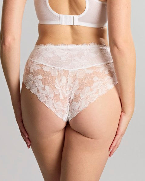 Woman wearing a white lace lingerie set on a plain background