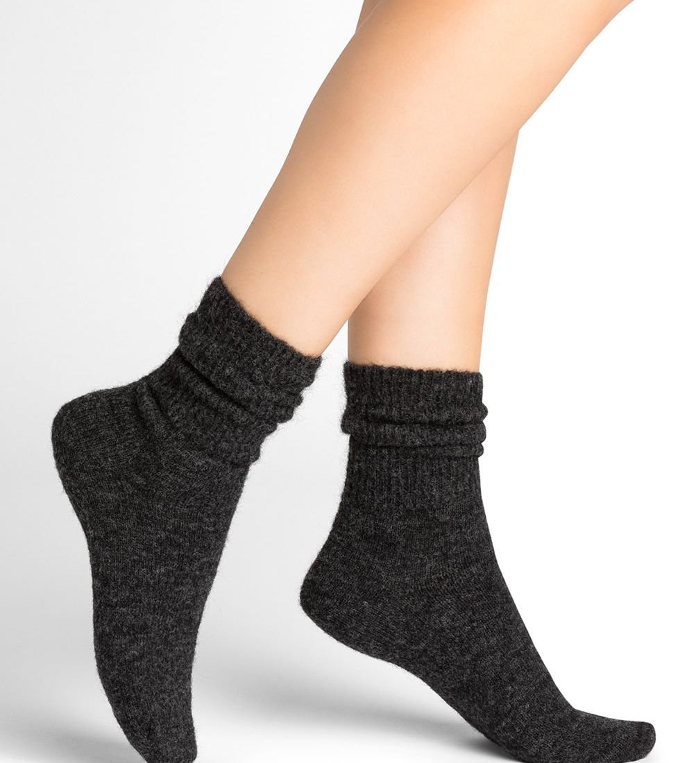 Model wearing Bleuforet Alpaca Wool Socks in Anthracite, mid-length women’s socks with gentle ribbing and reinforced heels and toes, available at The Foundation.

