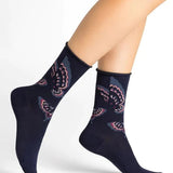 Woman wearing Bleuforet Velvet Cotton Butterflies Mid Socks in Encre with a glittery butterfly print, featuring a soft rolled cuff and reinforced heel, available at The Foundation.
