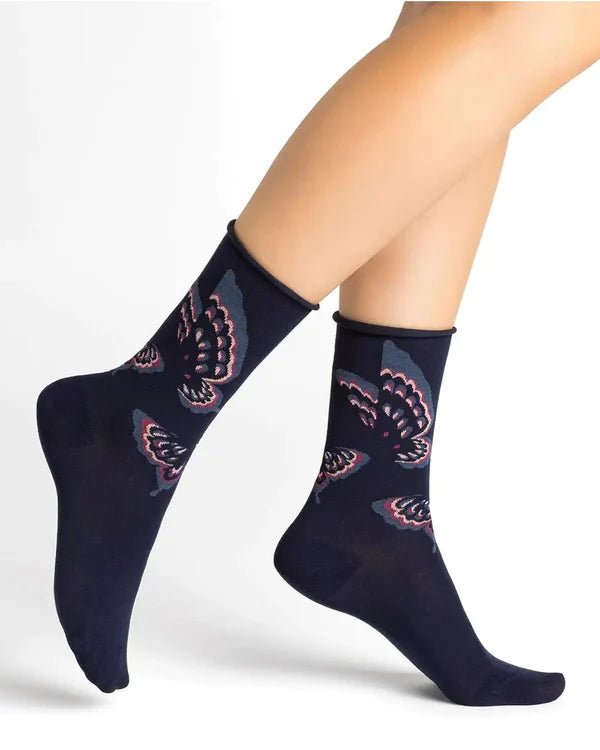 Woman wearing Bleuforet Velvet Cotton Butterflies Mid Socks in Encre with a glittery butterfly print, featuring a soft rolled cuff and reinforced heel, available at The Foundation.