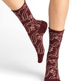 Model wearing Bleuforet Velvet Cotton Wild Flowers Mid Socks in Chianti, featuring a wild flower print and glittery threads, available at The Foundation.
