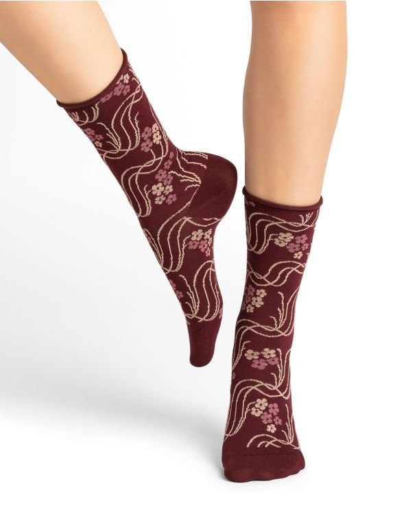 Model wearing Bleuforet Velvet Cotton Wild Flowers Mid Socks in Chianti, featuring a wild flower print and glittery threads, available at The Foundation.