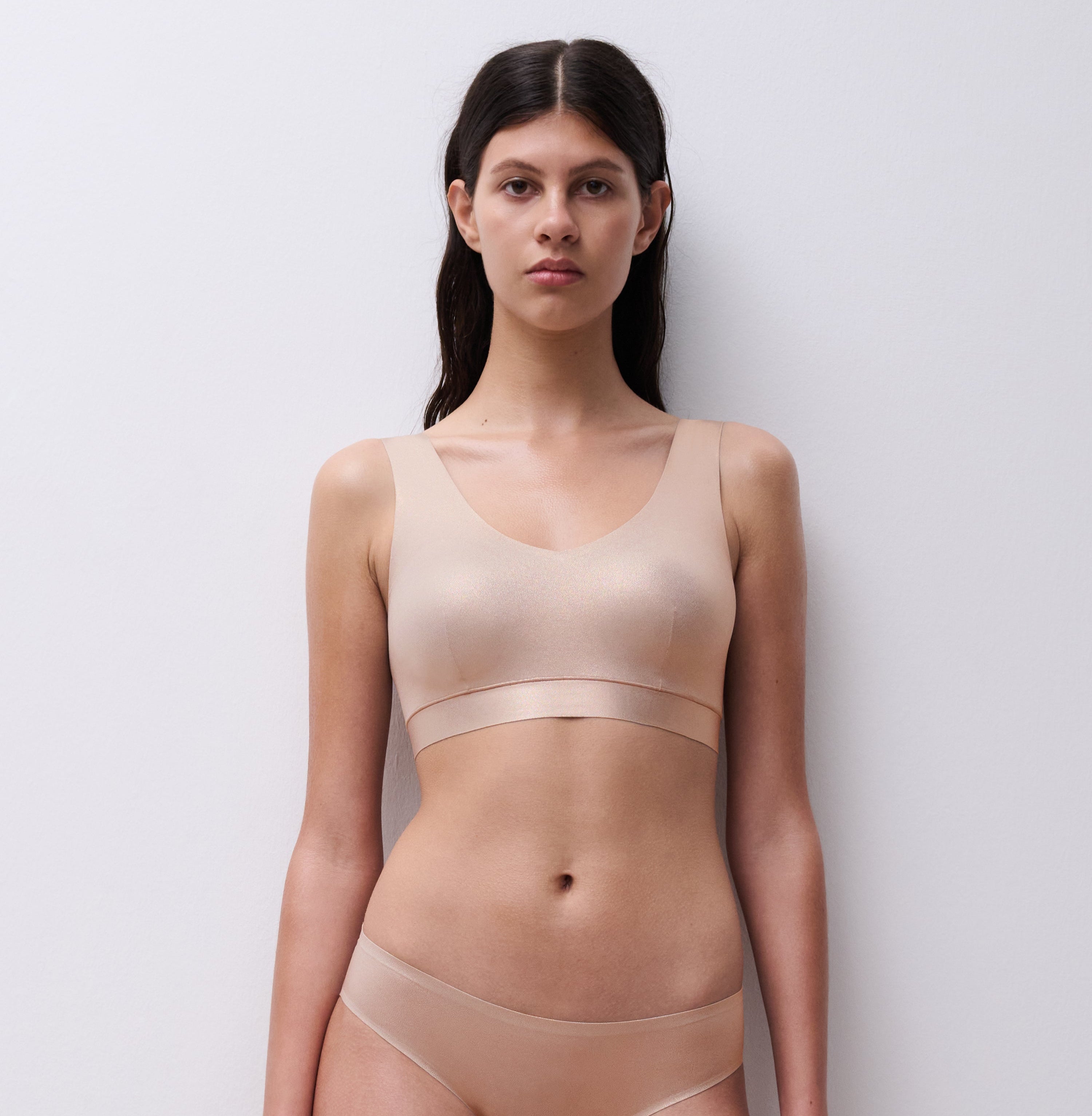 Woman wearing a beige tank top and underwear set against a white background